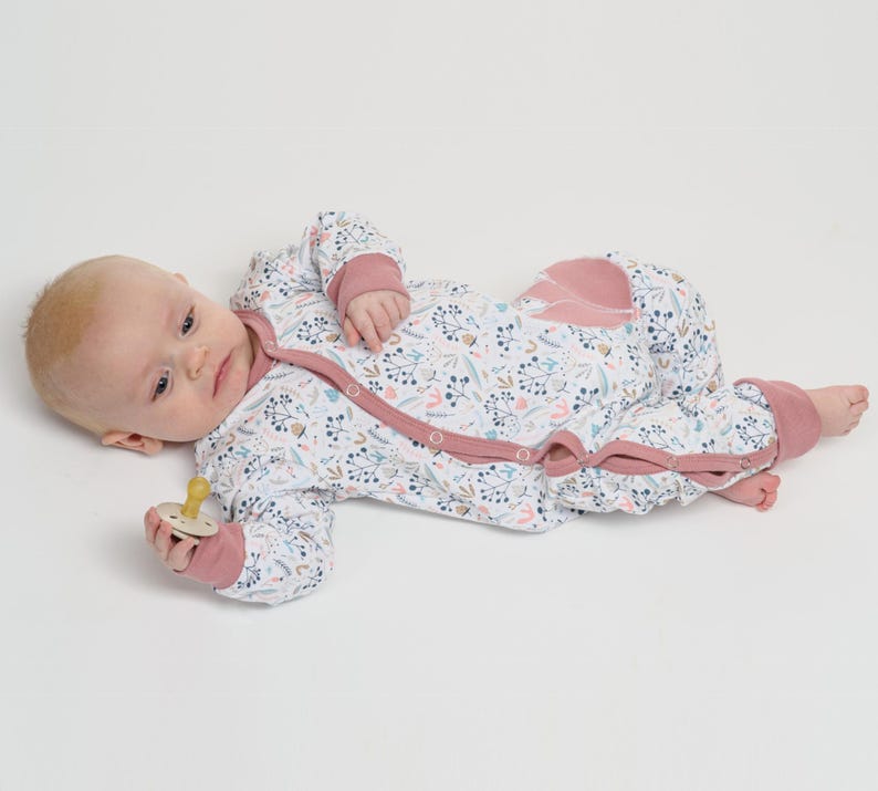 Neben Spielzeug liegend, rosa Einfassung entlang Knopfleiste sichtbar, strampler mit druckknöpfen, baby strampler pdf schnittmuster