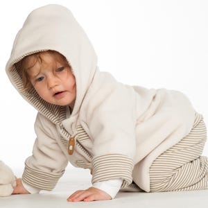 Kind krabbelt, Kapuze tief, gestreifte Hose und Fleecejacke, zeigt Bewegungsfreiheit des schnittmusters