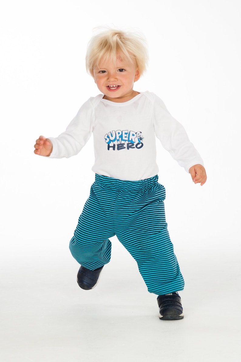 Kleinkind trägt eine gestreifte TORINO Babyhose aus Jersey mit elastischem Bund und Bündchen, lockere Passform mit viel Bewegungsfreiheit.