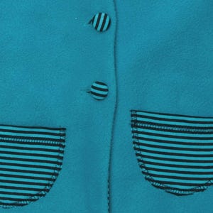 Detailaufnahme gestreifte aufgesetzte Taschen mit Zierknöpfen auf türkis Stoff, schnittmuster set baby, babyjacke schnittmuster pdf