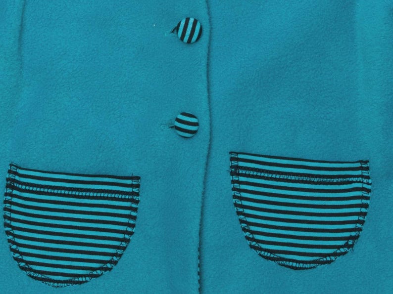 Detailaufnahme gestreifte aufgesetzte Taschen mit Zierknöpfen auf türkis Stoff, schnittmuster set baby, babyjacke schnittmuster pdf