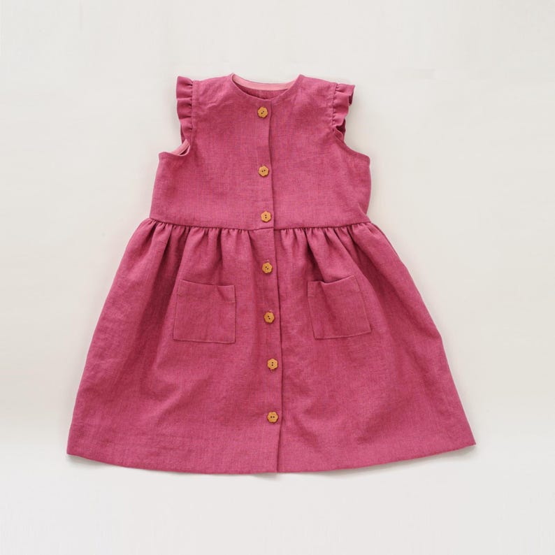 Flach gelegtes Vorderteil in Pink, sichtbare Knopfleiste mit Holzknöpfen und angedeutete aufgesetzte Taschen, Kleid mit Taschen Schnittmuster PDF