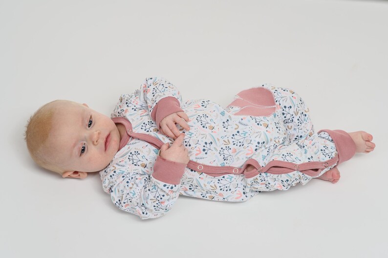 Kleine Aufnahme, Baby hält Spielzeug, Allover-Print und applizierte Tasche sichtbar, baby strampler pdf schnittmuster, anfänger schnitt
