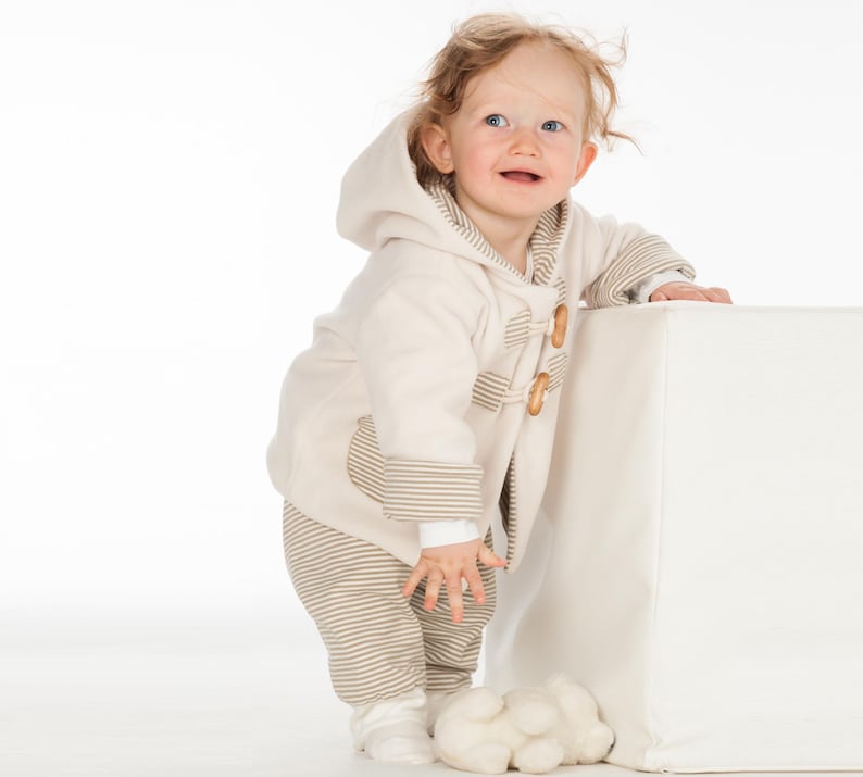 Kind steht halb hinter Würfel, creme Walkjacke mit Streifenfutter, betont kuschelige babyjacke schnittmuster