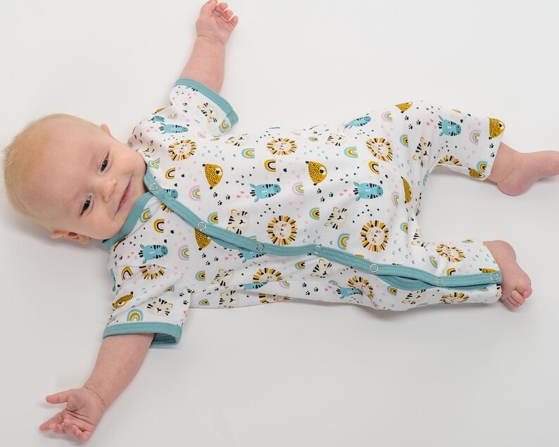 Fröhlich lächelndes Baby im Langarm-Strampler, lockere Passform, bunter Tierprint, jersey baby strampler schnittmuster
