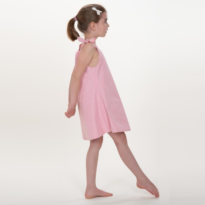 Kinder Kleid Schnittmuster 74 152, seitliche Gehpose im rosa karierten Trägerkleid, schwingende Saumkante