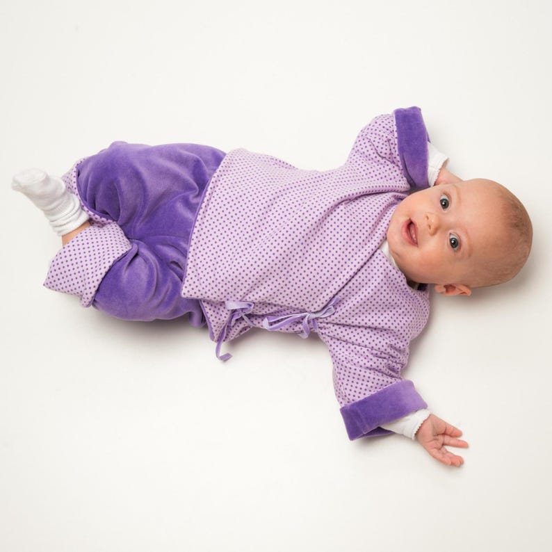 Seitlich liegend, Bindeband der Wickeljacke deutlich, Flieder-Lila Stoff mit weichem Griff, wickeljacke baby schnittmuster