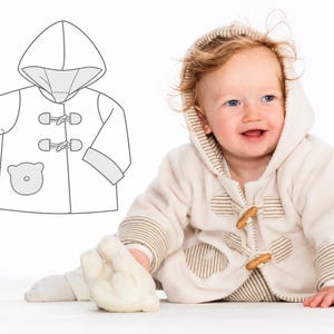 Könnte beinhalten: Eine cremefarbene Fleecejacke mit Kapuze, Knebelverschlüssen in Holzoptik und hellbraun gestreiften Abschlüssen an Ärmeln und Knopfleiste. Ein bärenförmiger Aufnäher befindet sich unten rechts. Eine Strichzeichnung der Jacke ist daneben abgebildet.