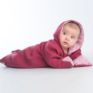 Seitliche Nahaufnahme, Baby liegt auf Bauch im rosa Fleece Kapuzenoverall, kuschelig, baby overall schnittmuster pdf