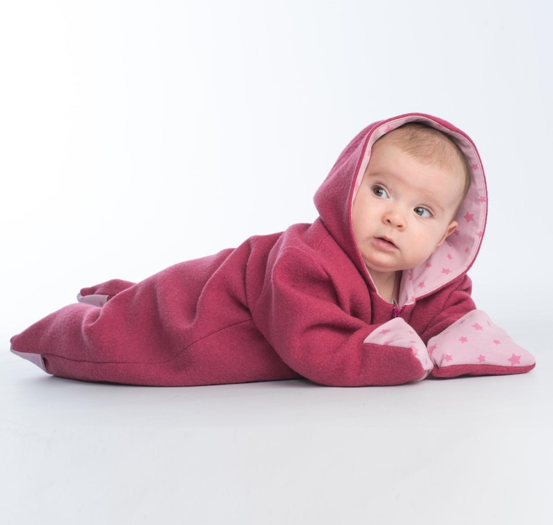 Seitliche Nahaufnahme, Baby liegt auf Bauch im rosa Fleece Kapuzenoverall, kuschelig, baby overall schnittmuster pdf