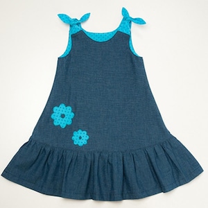 Mädchenkleid Schnittmuster PDF, flachliegendes blaues Trägerkleid mit Rüschensaum und Blumendeko