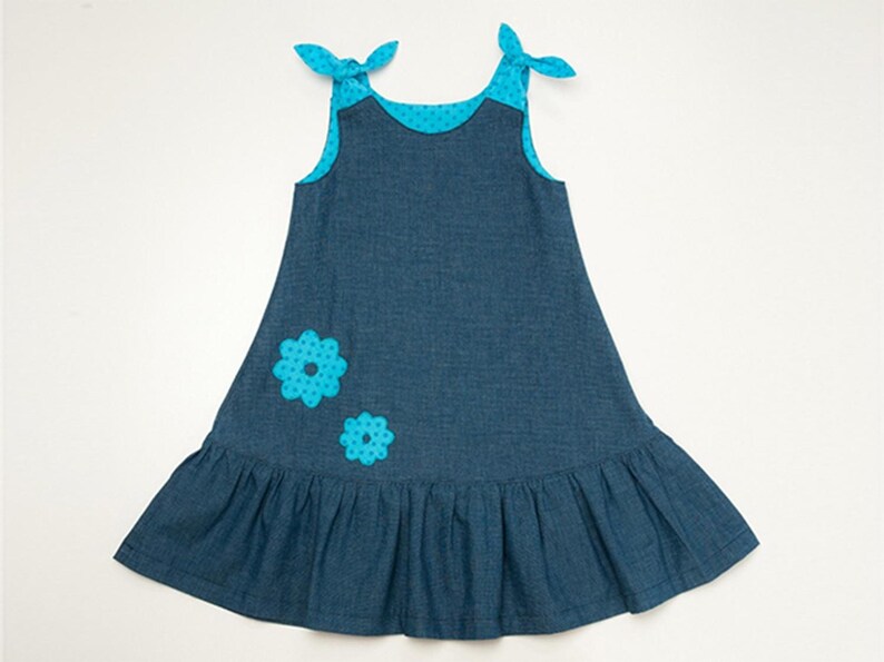 Mädchenkleid Schnittmuster PDF, flachliegendes blaues Trägerkleid mit Rüschensaum und Blumendeko