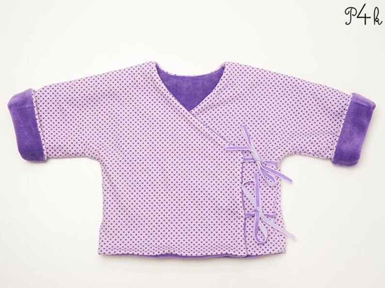 Vorderansicht der Jacke auf Fläche, breite dunkellila Bündchen und leichte Struktur, wendejacke baby schnittmuster beschrieben