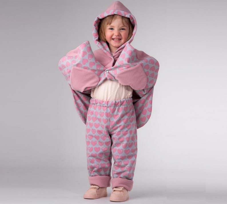 Kind spreizt Arme, runder Saum und Taschen sichtbar, Poncho Schnittmuster Baby, praktisches Anziehen