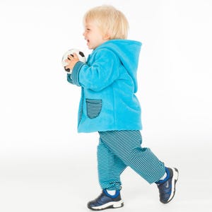 Laufende Kleinkind Seitenansicht im türkis Babyset, lockere Babyhose sichtbar, jacke hose baby schnittmuster