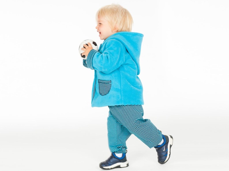 Laufende Kleinkind Seitenansicht im türkis Babyset, lockere Babyhose sichtbar, jacke hose baby schnittmuster
