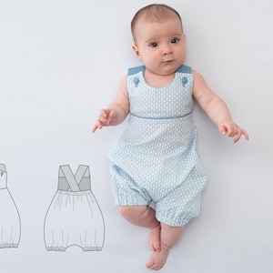 May include: A baby wearing a light blue and white patterned romper with blue straps. The romper has a crossover strap detail in the back. The romper is shown next to a line drawing of the romper.