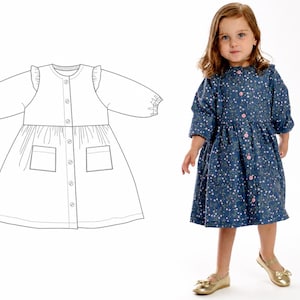 Mädchen im dunkelblauen, langärmeligen Kleid mit feinem Blumenmuster, rosa Knöpfen und aufgesetzten Taschen vor hellem Hintergrund, links die technische Zeichnung des Kleidschnittmusters.