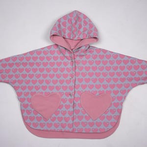 Flach gelegt gemusterte Seite außen, sichtbare Taschenherzen, Wendeponcho Kinder zum Nachnähen