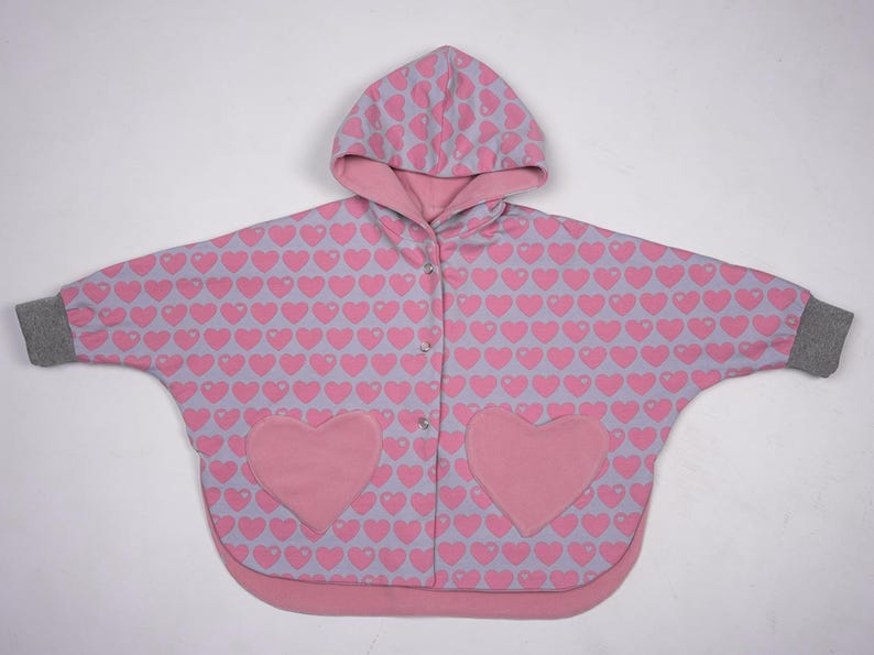 Flach gelegt gemusterte Seite außen, sichtbare Taschenherzen, Wendeponcho Kinder zum Nachnähen
