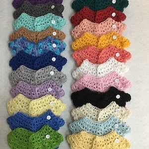 May include: A collection of 24 crocheted cardigans in various colors, including purple, green, red, pink, yellow, blue, gray, white, black, and beige. Each cardigan is numbered 1 through 24.