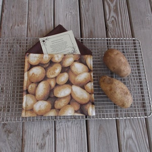 May include: A brown fabric pouch with a potato print design. The pouch is on a silver wire rack with two potatoes next to it.