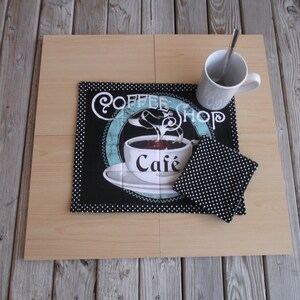 Peut inclure: Un set de table noir et blanc sur le thème du café avec des pois blancs. Le set de table présente une tasse de café avec le texte "Coffee Shop Cafe". Deux sous-verres noirs et blancs à pois sont également inclus.