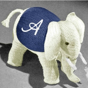 May include: A white crocheted elephant wearing a blue knitted vest with a white letter 'A' on the front.