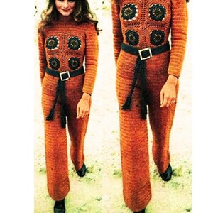 May include: A crocheted jumpsuit in a burnt orange color with a black belt and tassel. The jumpsuit features a geometric pattern with crocheted flowers.