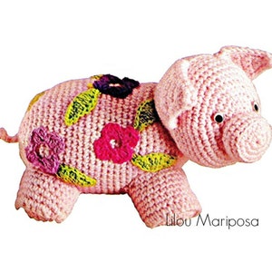 May include: A pink crocheted pig with a flower design. The pig has a curly tail and black eyes. The flowers are pink, purple, and yellow.