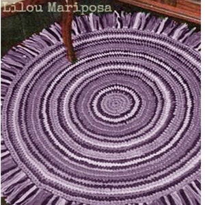 May include: A purple and white crocheted rug with a fringe border. The rug has a circular design with concentric circles.