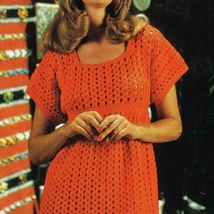 May include: A crocheted dress with a loose fit and short sleeves. The dress is made of a bright orange yarn and has a simple, openwork design.