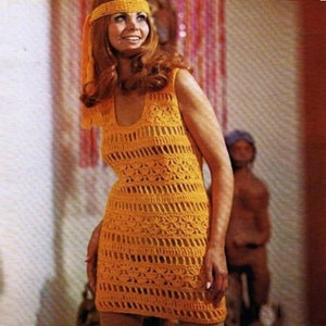 May include: A woman wearing a sleeveless, yellow crochet dress with a crocheted headband. The dress has a scoop neckline and a loose fit.