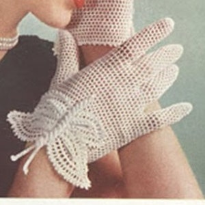 Puede incluir: Un par de guantes de ganchillo blancos con un delicado diseño de mariposa en la muñeca.