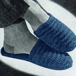 May include: A pair of blue knitted slippers with a textured pattern. The slippers are worn on a person's feet.