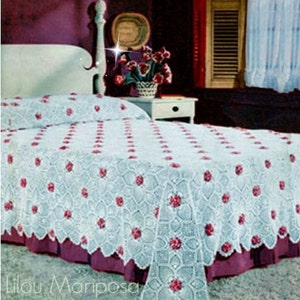 May include: A white crocheted bedspread with a floral design. The bedspread has a scalloped edge and is made with a delicate, lacy pattern. The bedspread is on a bed with a white headboard and a burgundy footboard.