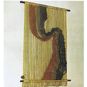 May include: A macramé wall hanging with a wooden dowel at the top and bottom. The piece features vertical strands of yellow yarn, with sections of brown, orange, and black macramé detailing. The bottom edge has a fringe.