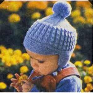 May include: A blue knitted baby hat with a pom-pom on top. The hat has a textured pattern and ear flaps.