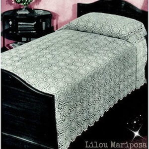 May include: A white crocheted bedspread with a delicate floral pattern, draped over a black wooden bed frame.