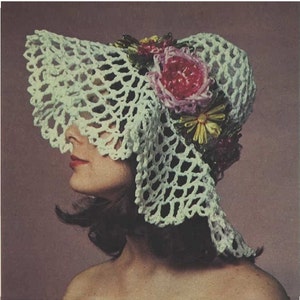 May include: A white crocheted sun hat with a wide brim and a floral embellishment. The flowers are pink, yellow, and green.