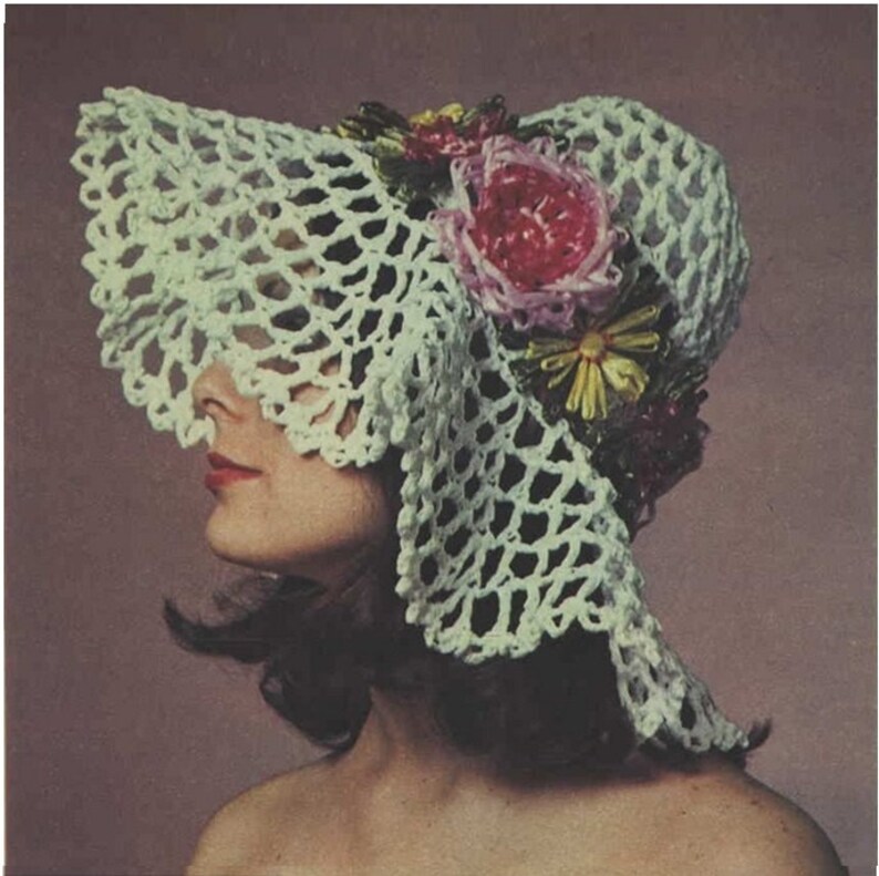 May include: A white crocheted sun hat with a wide brim and a floral embellishment. The flowers are pink, yellow, and green.