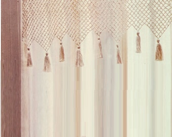 May include: A beige crocheted curtain with a fringe of tassels. The curtain is made of a delicate, open-weave fabric.
