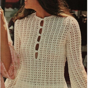 May include: A white crochet dress with a button-up front and long sleeves. The dress has a loose fit and a delicate, open-weave pattern.