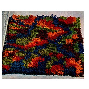 Op de afbeelding: Een kleurrijk, veelkleurig, pluche vloerkleed met een geometrisch patroon. Het vloerkleed is gemaakt van garen en heeft een verscheidenheid aan kleuren, waaronder blauw, groen, oranje en rood.