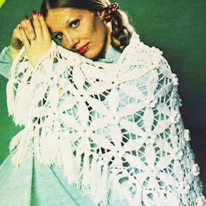 May include: A white crocheted shawl with a delicate floral pattern and fringe trim. The shawl is draped over a woman's shoulders.