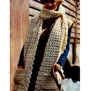May include: A crocheted scarf with two pockets. The scarf is cream colored and has a lacy pattern. The pockets are on the bottom of the scarf and are also crocheted.