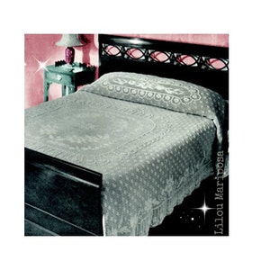 May include: A white crocheted bedspread with a floral design on a black bed frame. The bedspread has a scalloped edge and is made of delicate crochet lace.