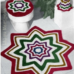 May include: A crocheted toilet seat cover and a matching rug in the shape of a star. The cover and rug are red, white, green, purple, and gold. The rug has a multi-layered star design.