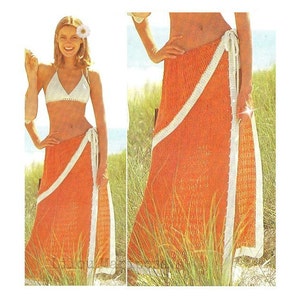 Peut inclure: Une jupe en crochet orange avec une bordure blanche. La jupe est nouée à la taille et a un design long et fluide.