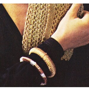 May include: Two brown and gold bracelets on a person's wrist. The bracelets are made of woven material and have a natural, rustic look.
